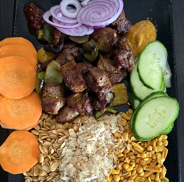 Nepali platter with grilled meat, beaten rice, peanuts, achar and fresh vegetables